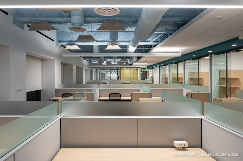 Open plan workspace with glass partitions and exposed ceiling at a technology company office
