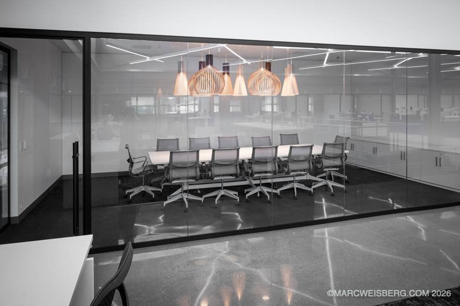 Glass walled conference room with pendant lights and polished concrete floor at a tech office