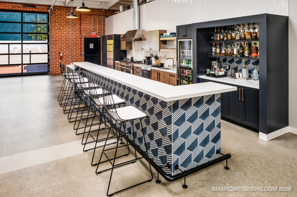 Tech office kitchen with patterned tile bar, stools and brick wall