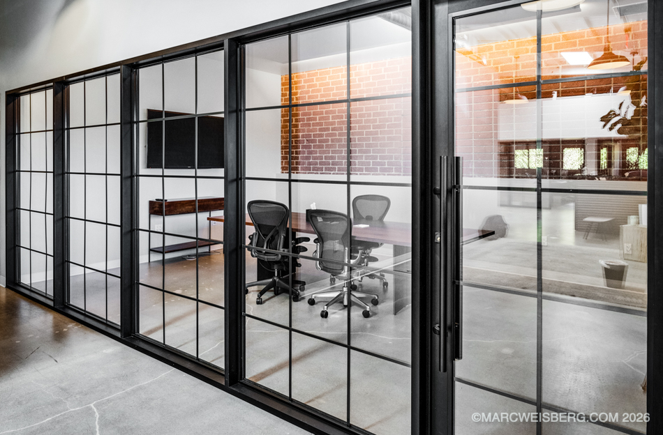Black framed glass conference room with brick wall at a tech company office